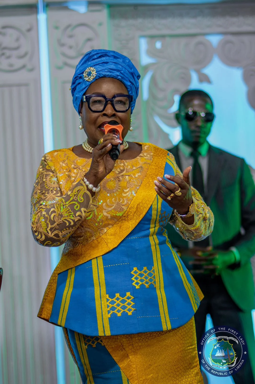 Her Excellency Kartumu Yarta Boakai speaking into a microphone at a public event.